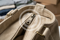 Custom zipper pull with engraved logo on canvas tote bag showing premium branding detail